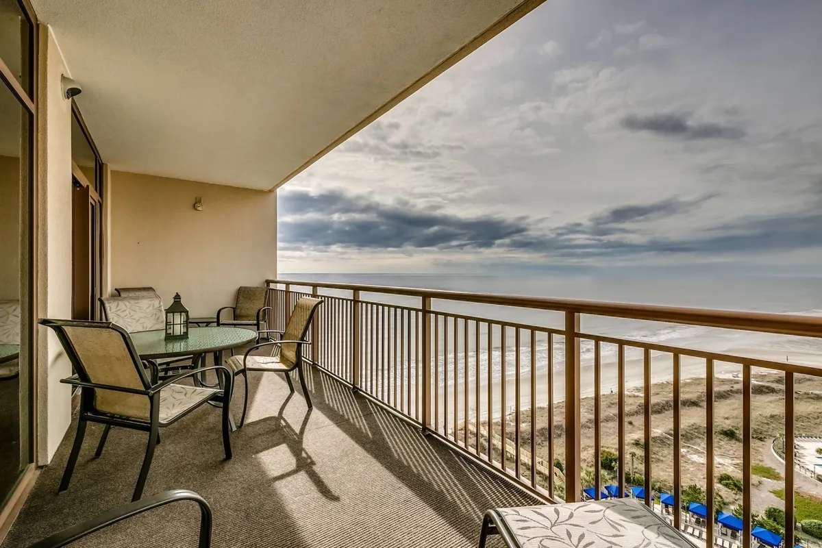 The hero image features a spacious balcony overlooking the shimmering Atlantic Ocean, with a sleek glass table surrounded by comfortable chairs, inviting guests to relax, dine, and soak in the breathtaking sea views. The tranquil setting is perfect for enjoying sunrises, sharing meals, or unwinding beneath the stars, all while the gentle sound of waves provides a soothing backdrop.