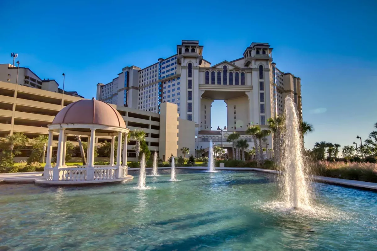A serene exterior view showcasing a peaceful fountain, elegant gazebo, and striking building architecture. The landscape invites group relaxation and photo opportunities in a luxurious, resort-like setting.